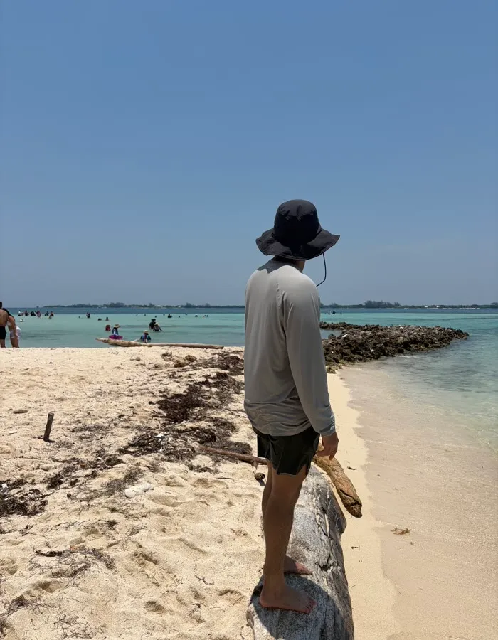 Persona de espaldas frente al mar, en una playa de arena clara